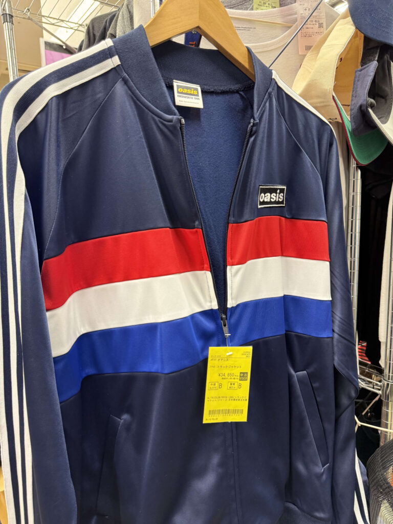 Close-up of an Oasis Knebworth commemorative track jacket, with 'Knebworth' visible on the tag.