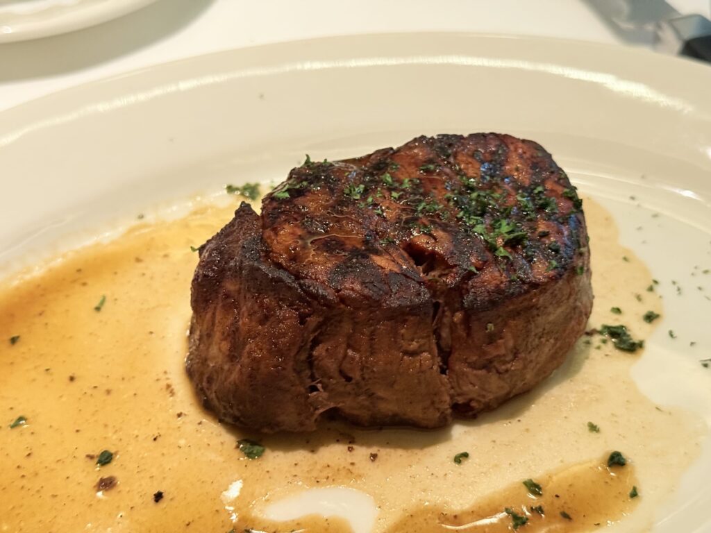 A filet mignon steak served on a white plate, sliced to reveal its beautiful pink, medium-rare center.