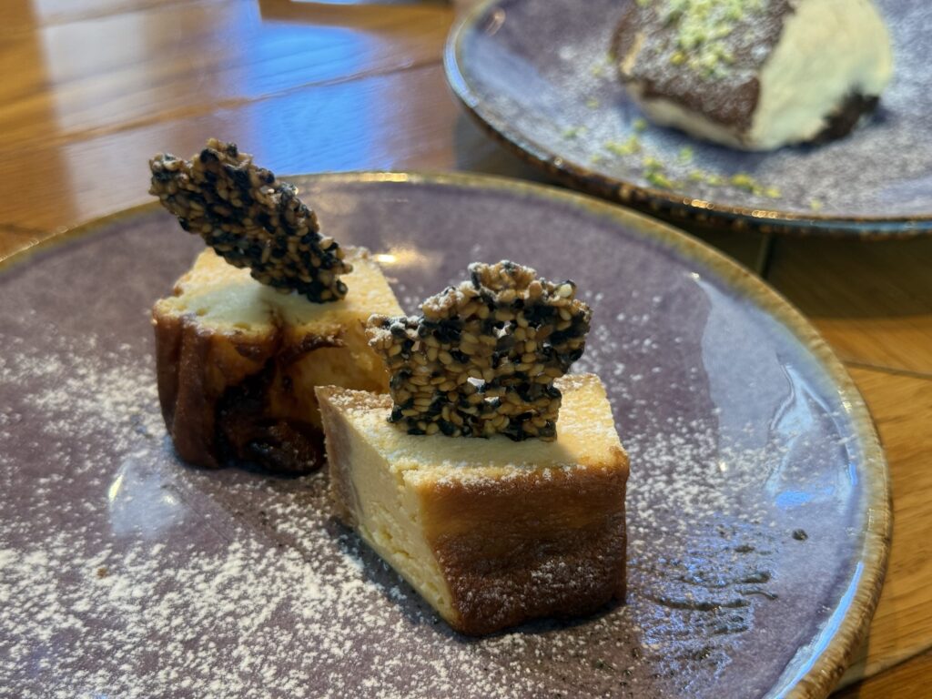A close-up of a slice of cheesecake generously topped with black and white sesame seeds.
