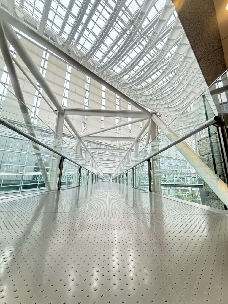 Low-angle shot of a sturdy, modern bridge spanning an indoor atrium, highlighting its steel structure and lighting.