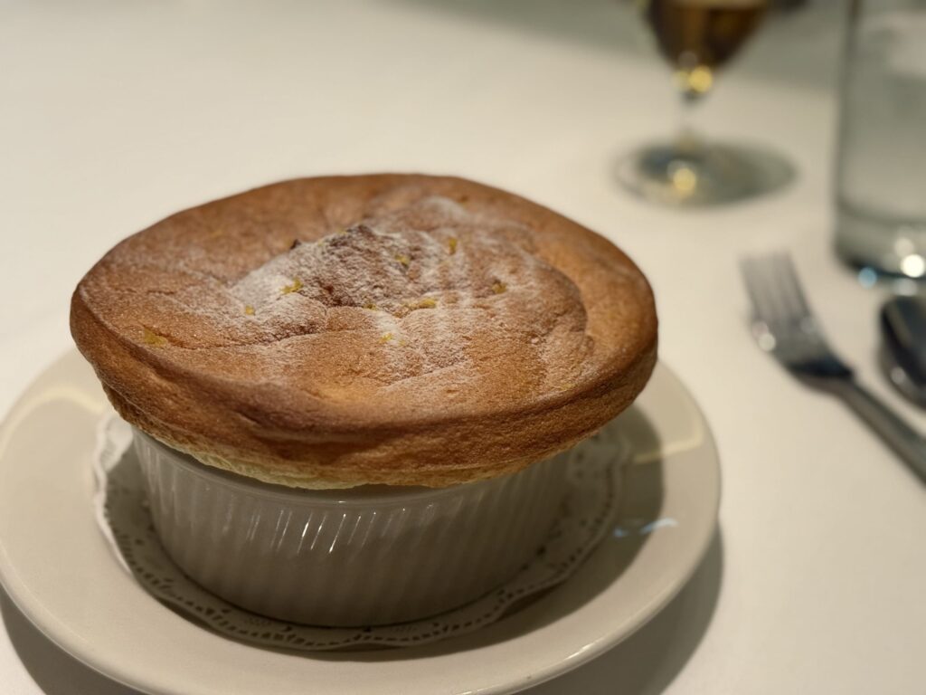 白いお皿にのった、粉砂糖が振りかけられたふわふわのスフレケーキ。