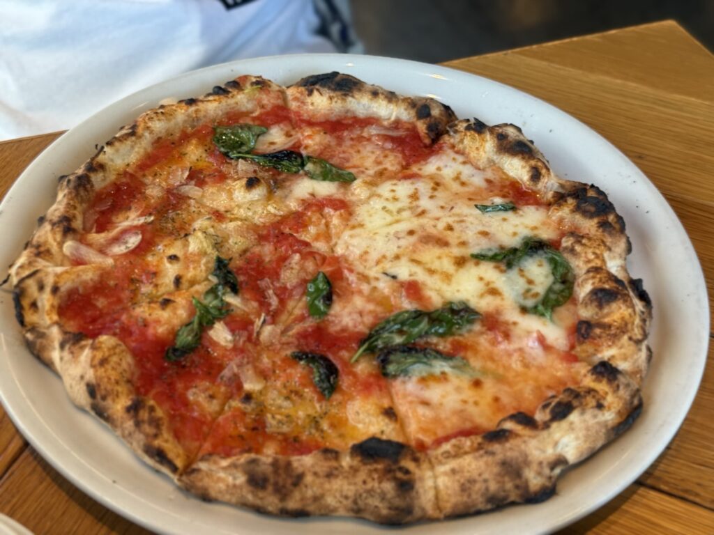 Half Margherita and half Marinara pizza on a wooden board.