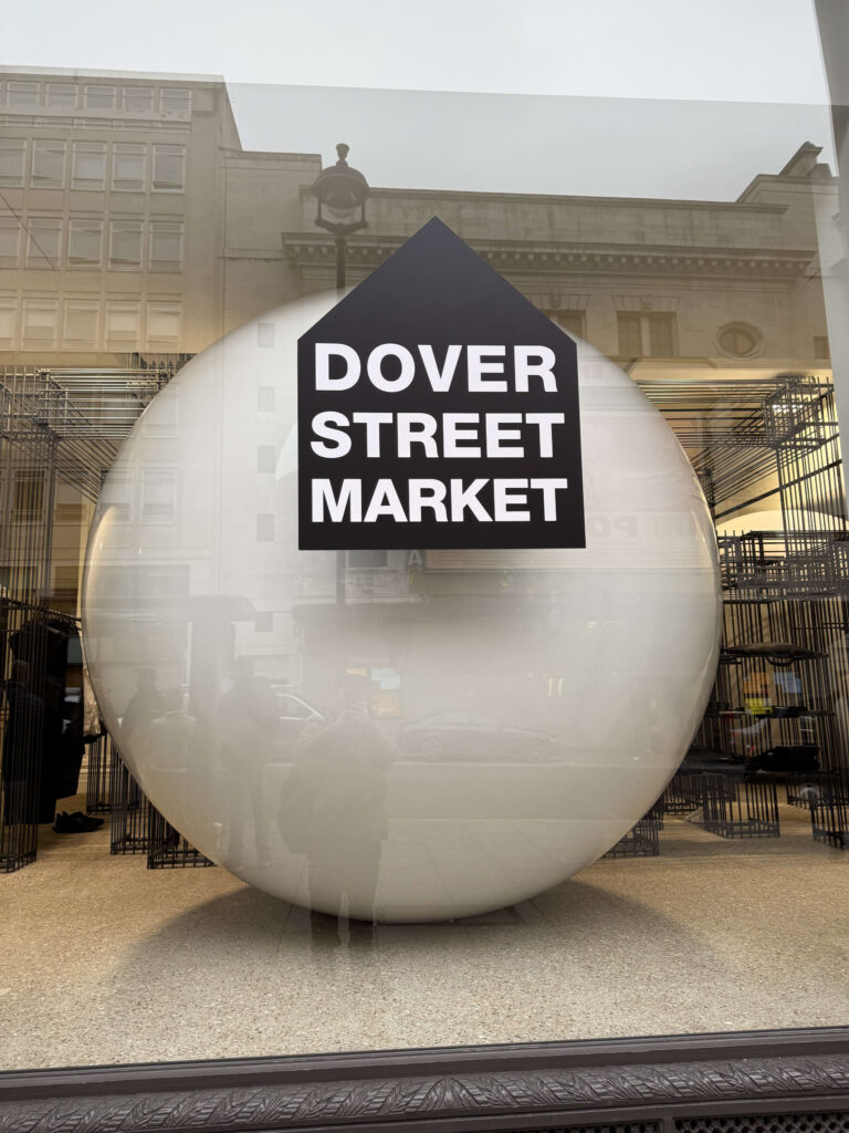 Show window of Dover Street Market London with a metallic object against a pink background.