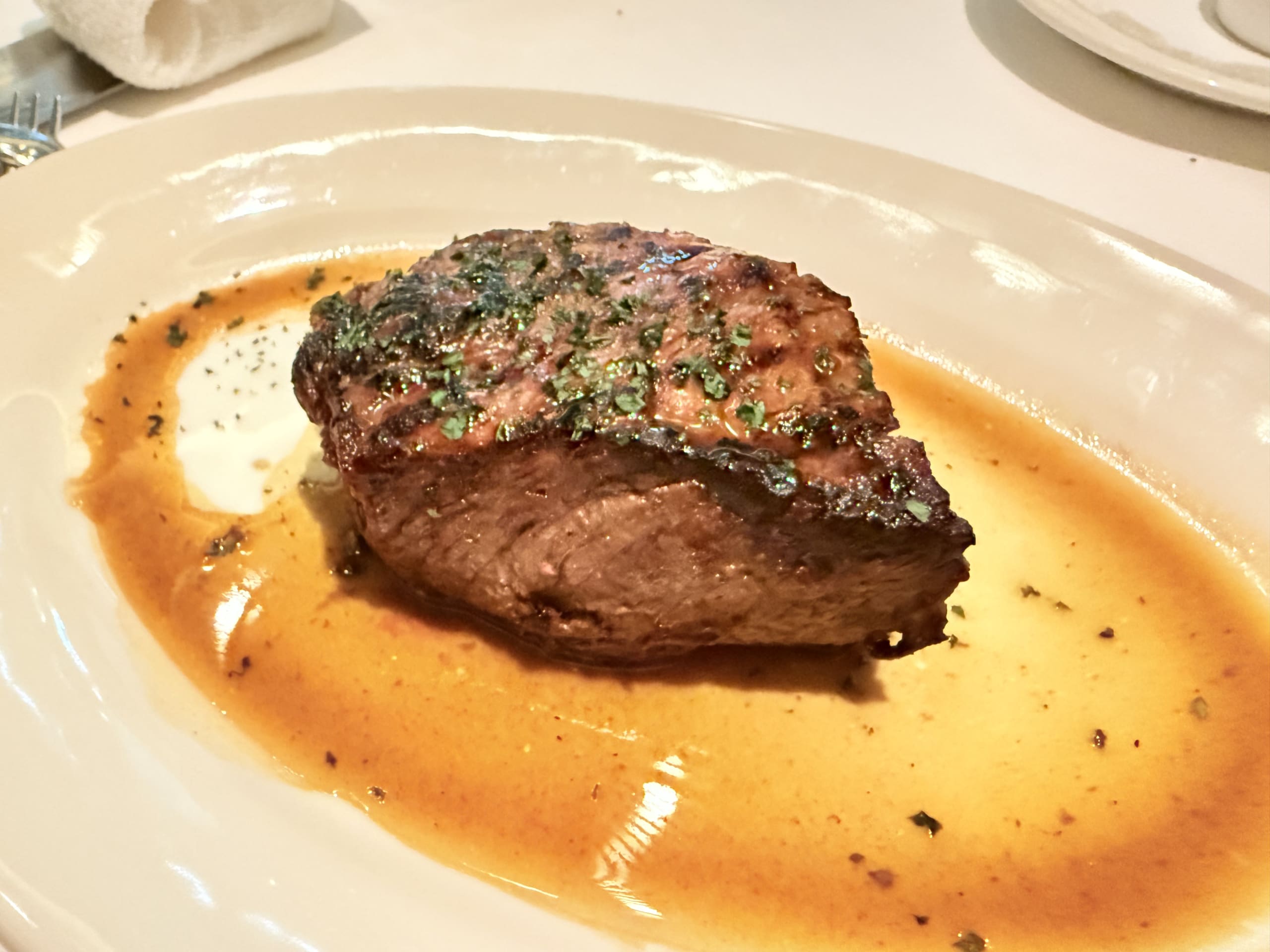 A thick-cut Prime New York steak, sliced and arranged on a white plate. The cross-section shows a juicy medium-rare center with a well-seared, dark crust.