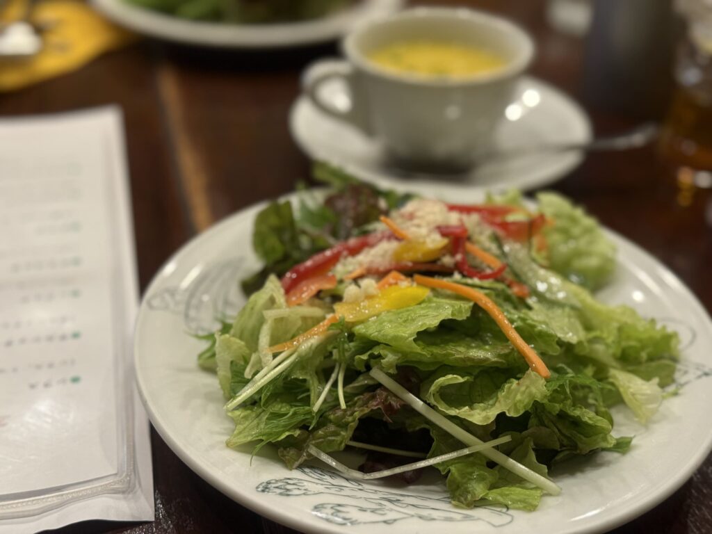 A colorful salad from PIZZA DA BABBO on a white plate, showing lettuce, tomatoes, corn, and purple cabbage.