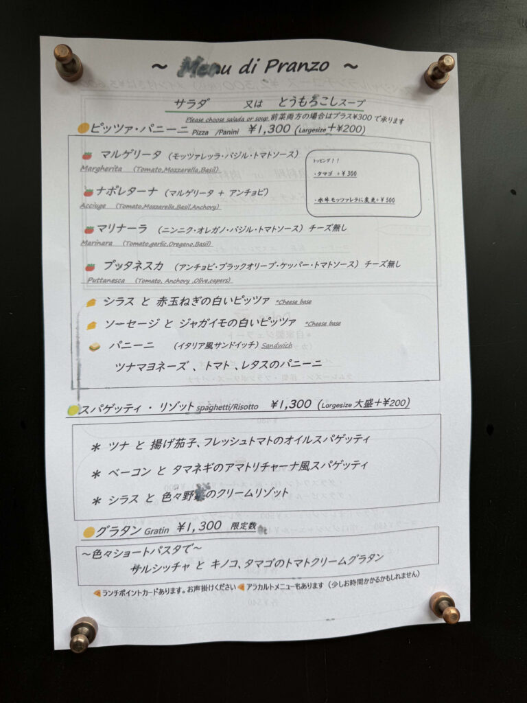 PIZZA DA BABBOの店先に掲示されたランチメニュー。木目調の壁に貼られ、ピザとパスタのセットが手書き風文字で記載されている。
