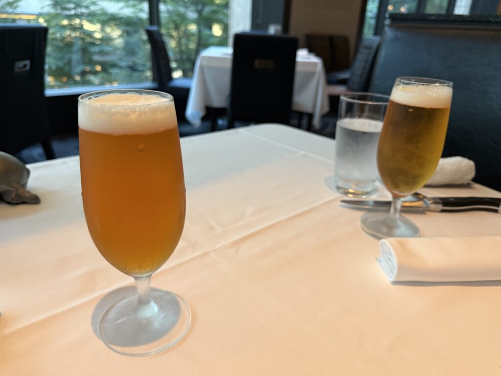 木製のテーブルの上に置かれた、泡立つIPAビールが入ったグラス。