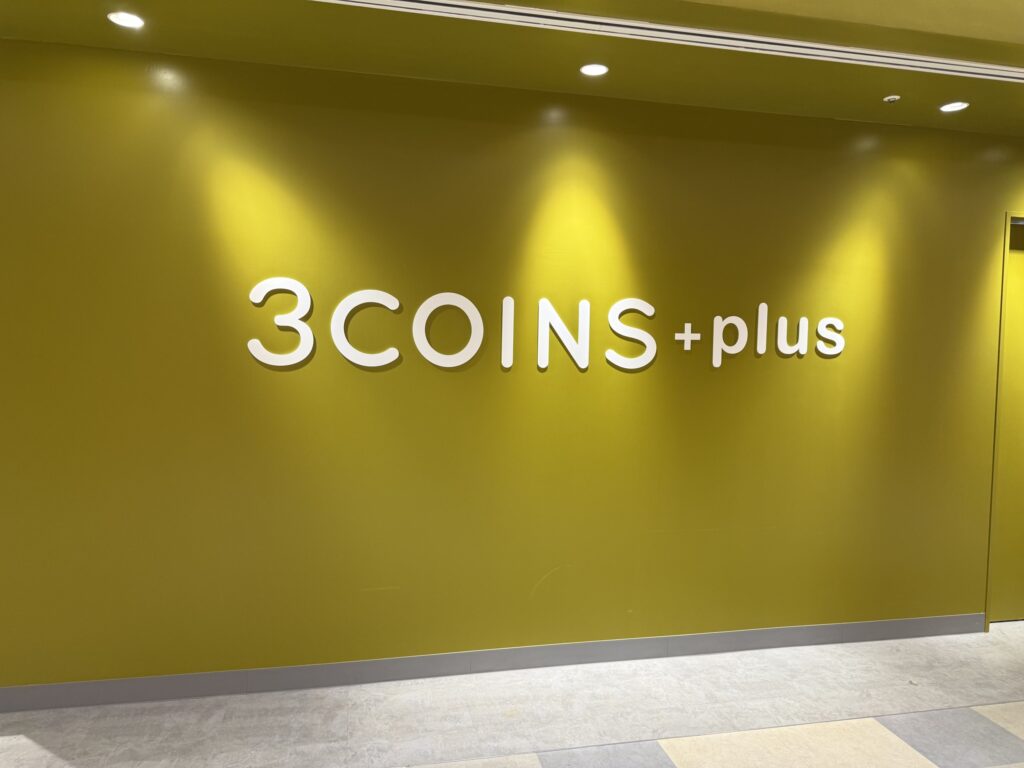 3COINS+店舗の外観。白い壁に緑色の大きなロゴと店名が特徴的。