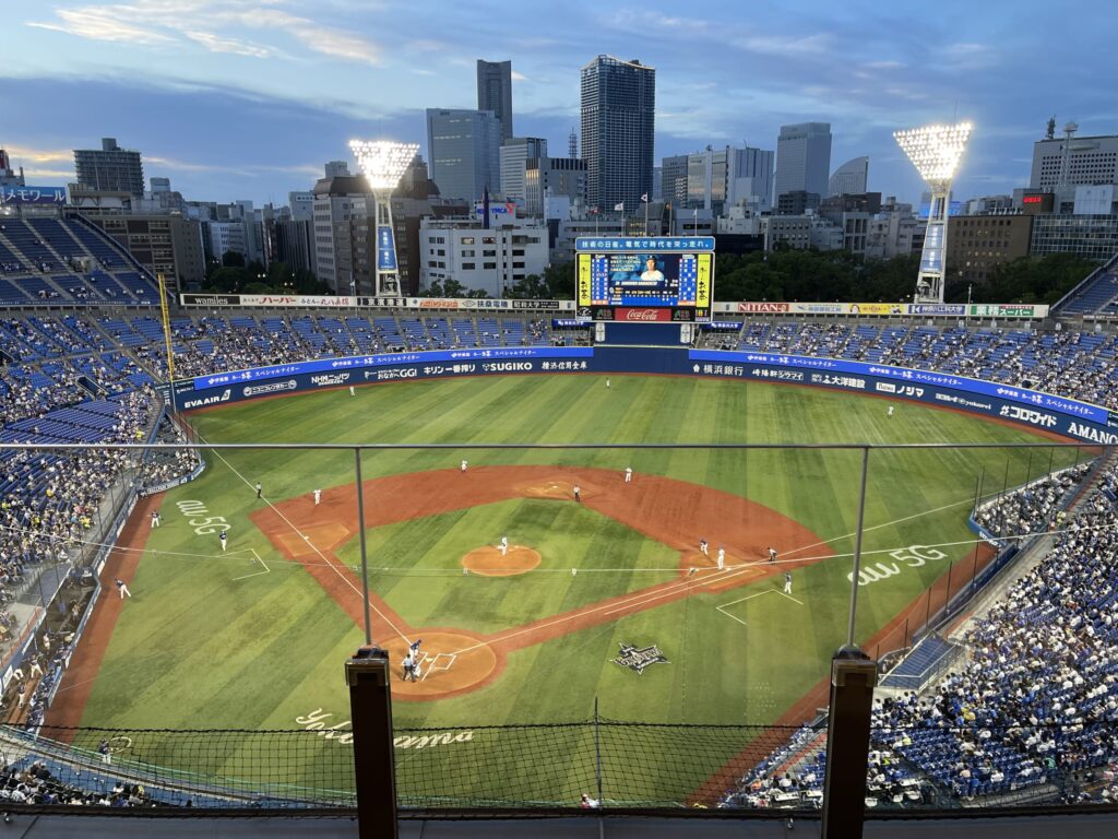 ホテルのSTAR SUITEの部屋の窓際に置かれた椅子と、窓の外に広がる夕焼けの都市のパノラマビュー。