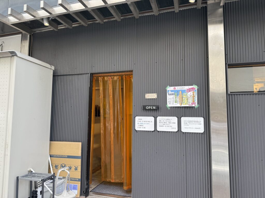 Exterior of Soba-Usa, a soba noodle restaurant, featuring its characteristic black wall and wooden sign.