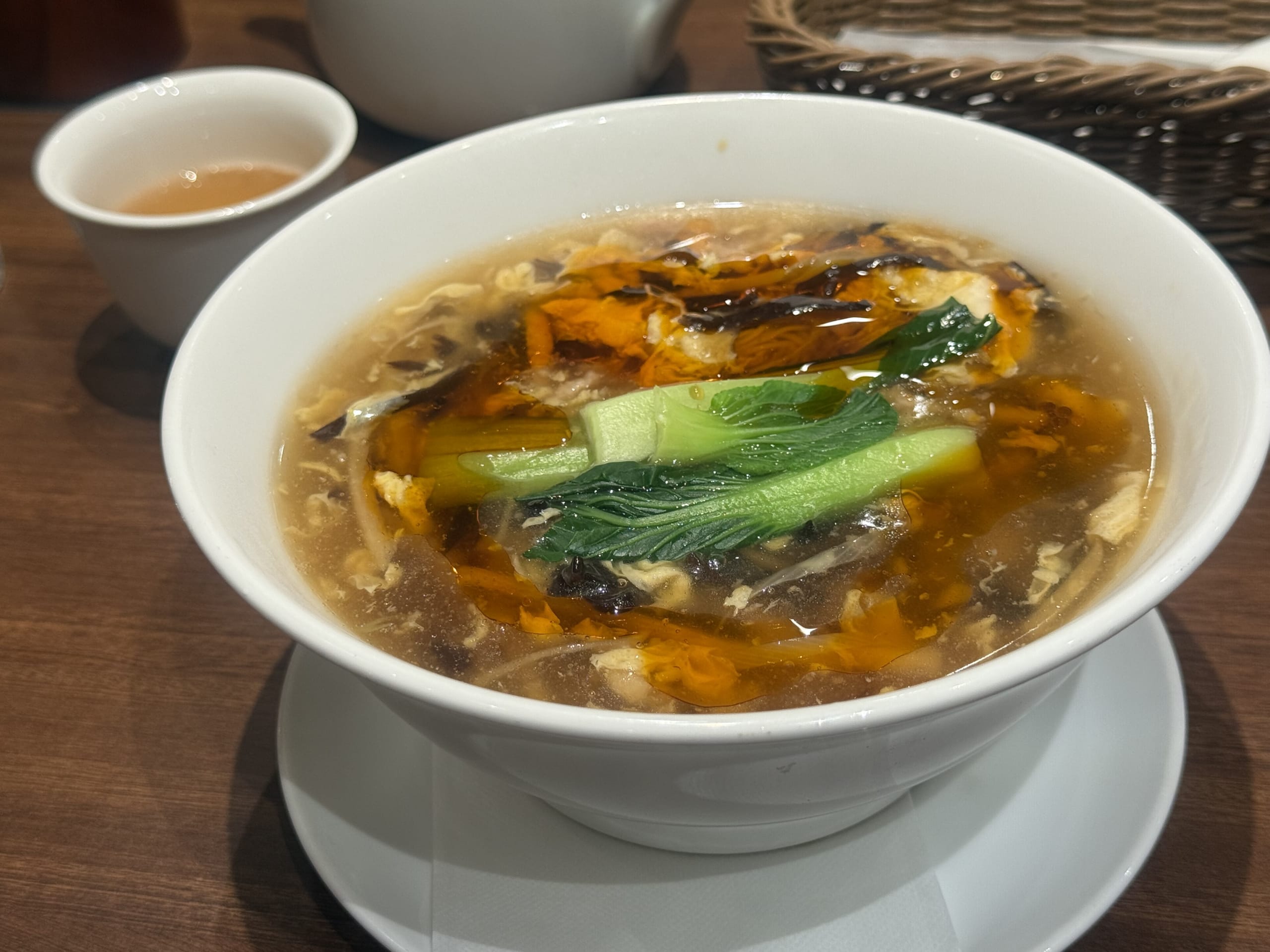 赤いスープに細切りの野菜や溶き卵などの具材がたっぷり入ったサンラータン麺のクローズアップ写真