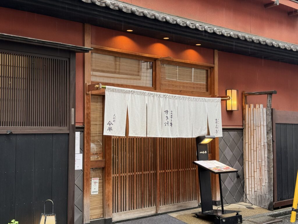 人形町今半の店舗外観。瓦屋根と白い壁、入り口に大きな暖簾がかかっている伝統的な日本の建物。
