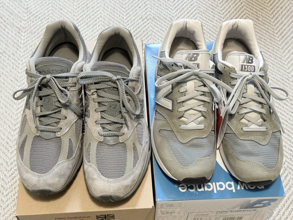 Two pairs of New Balance sneakers on a concrete-style floor: a grey U1300JP on the left, and a brown thisisneverthat x 991v2 on the right.