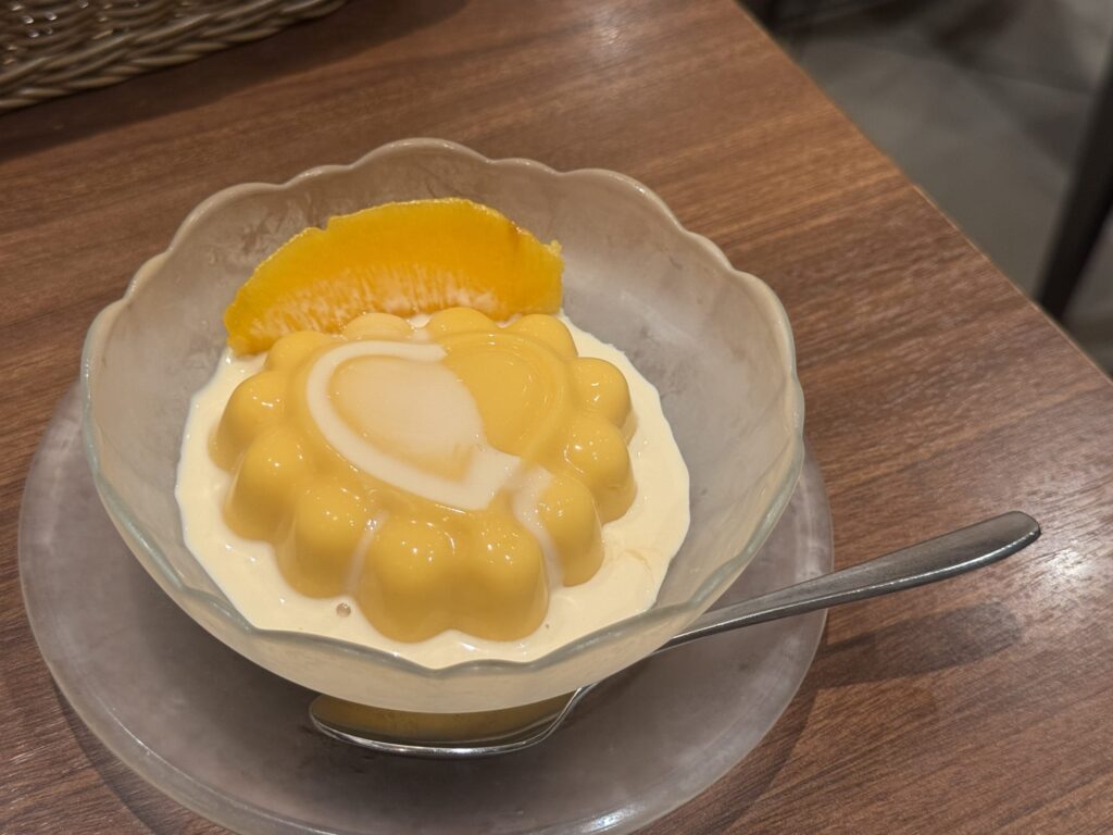 Mango pudding on a white plate, garnished with goji berries and mint.