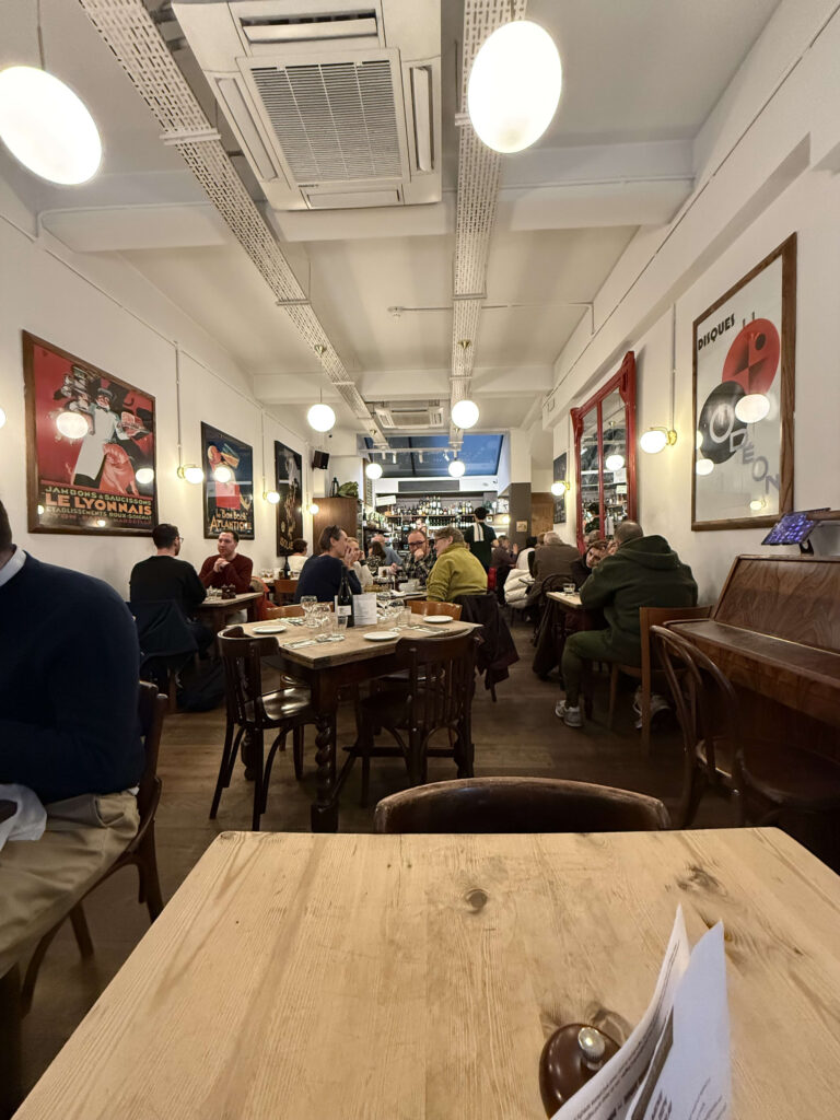 Pierre Victoire Sohoの温かみのある店内。木製のテーブルと椅子が並び、壁には絵画が飾られている。