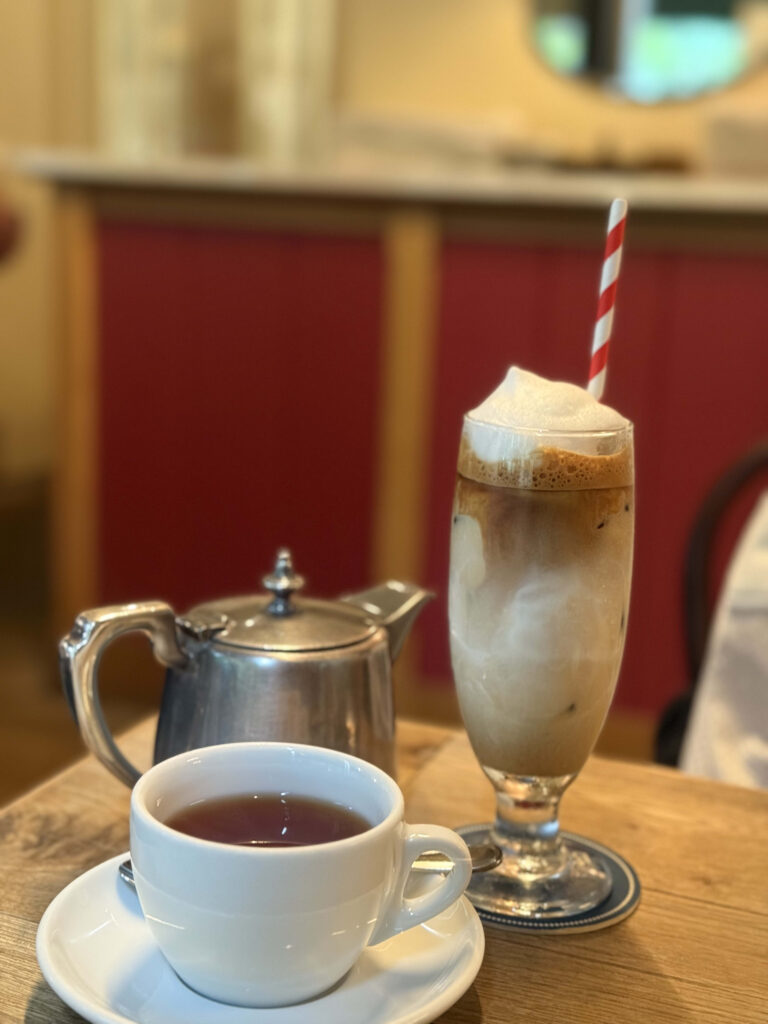 木製のテーブルに置かれた、ラテアートが施されたカフェオレとガラスカップに入った紅茶。