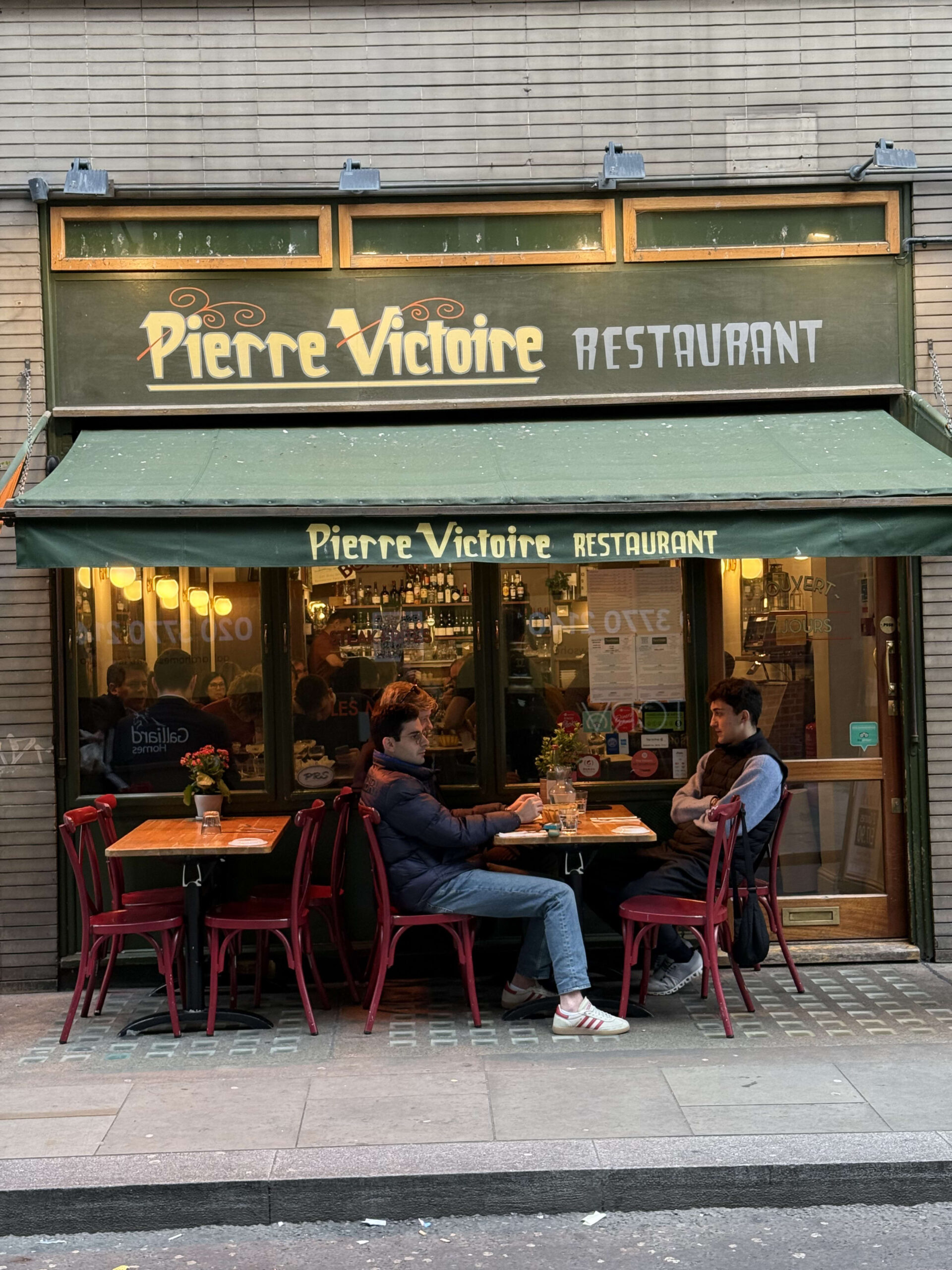 Exterior of Pierre Victoire Soho restaurant in London, showing its red facade and outdoor terrace seating being used in November.