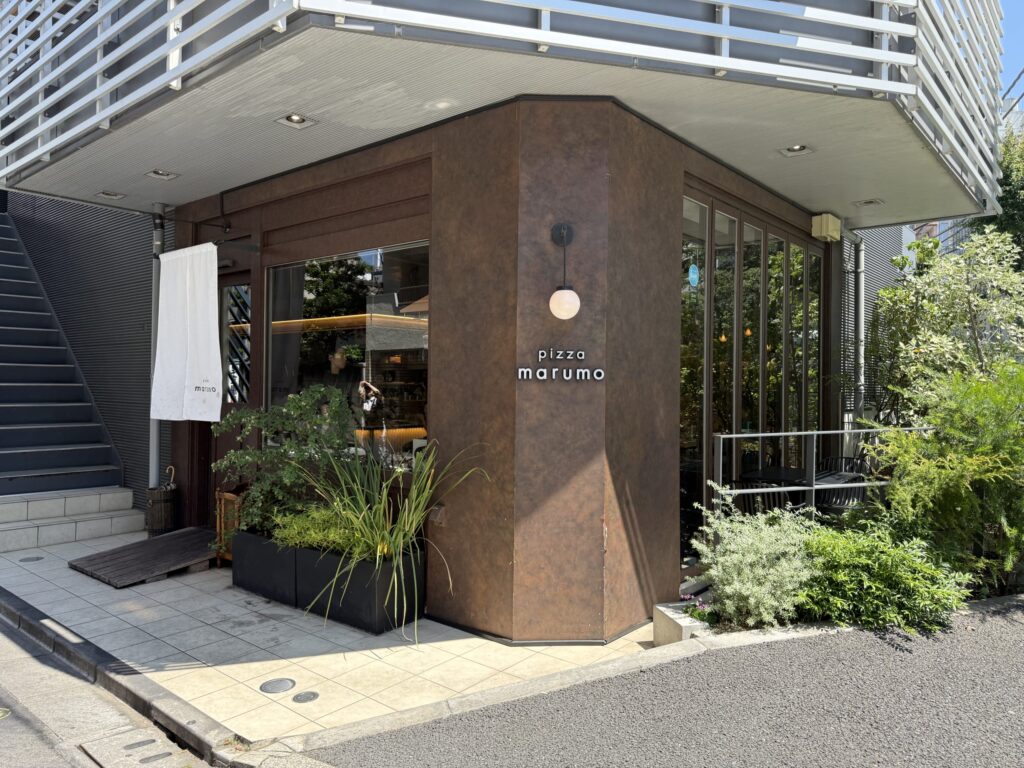 Stylish exterior of pizza restaurant 'Pizza maruno' with a terrace seat.