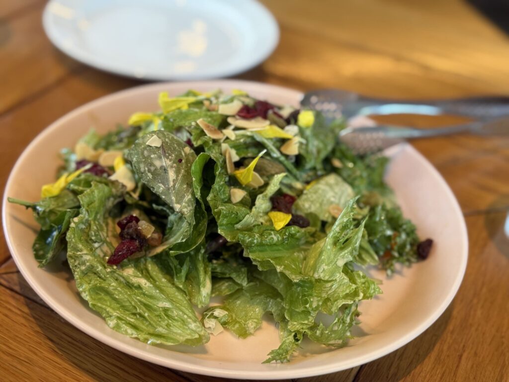 Maruno's S-size salad, a colorful mix of vegetables served on a white plate on a wooden table
