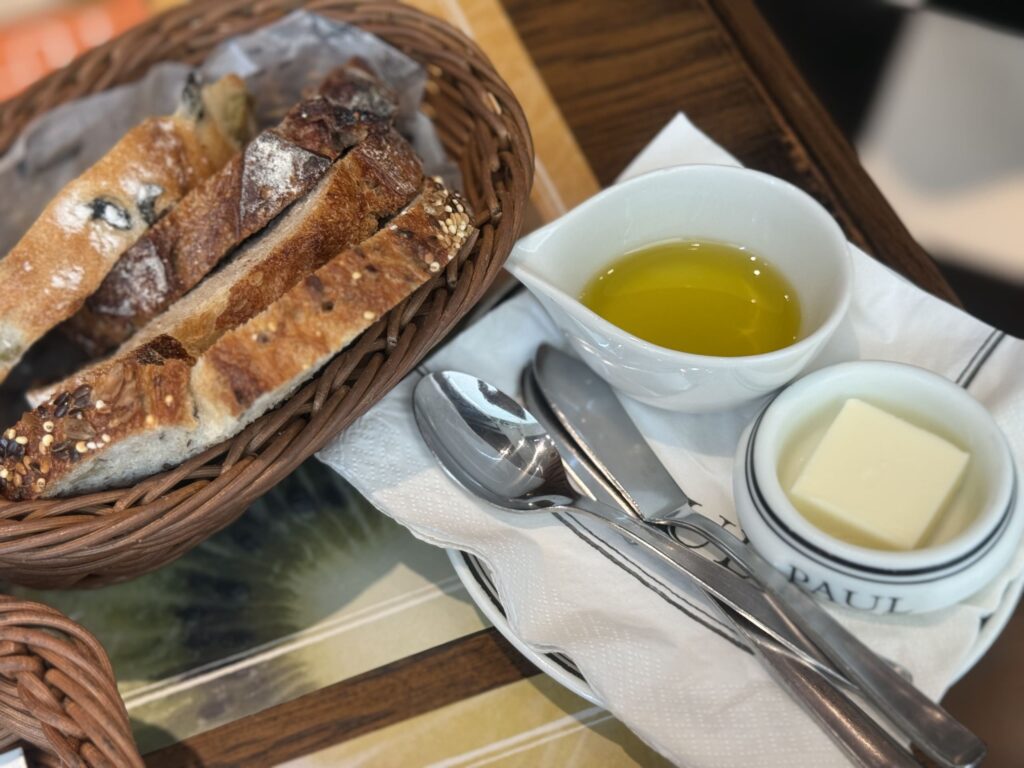 Slices of bread, olives, and butter arranged on a wooden cutting board.