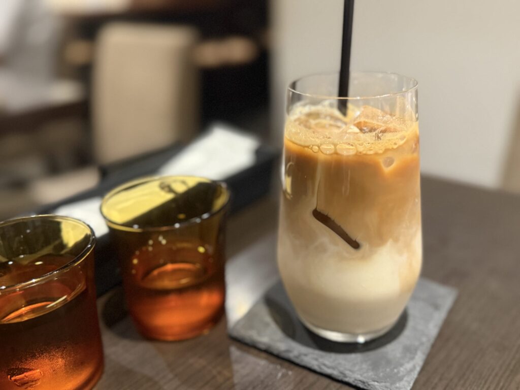 木製のトレイに乗せられた、層になった豆乳ラテアイス。背の高いグラスにストローが差してある。