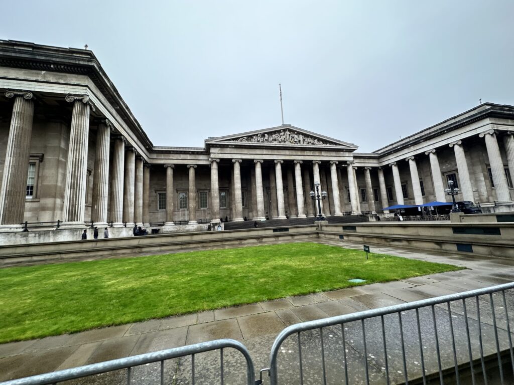 青空の下に佇む大英博物館の正面玄関。イオニア式の柱が並ぶ壮大な建物。
