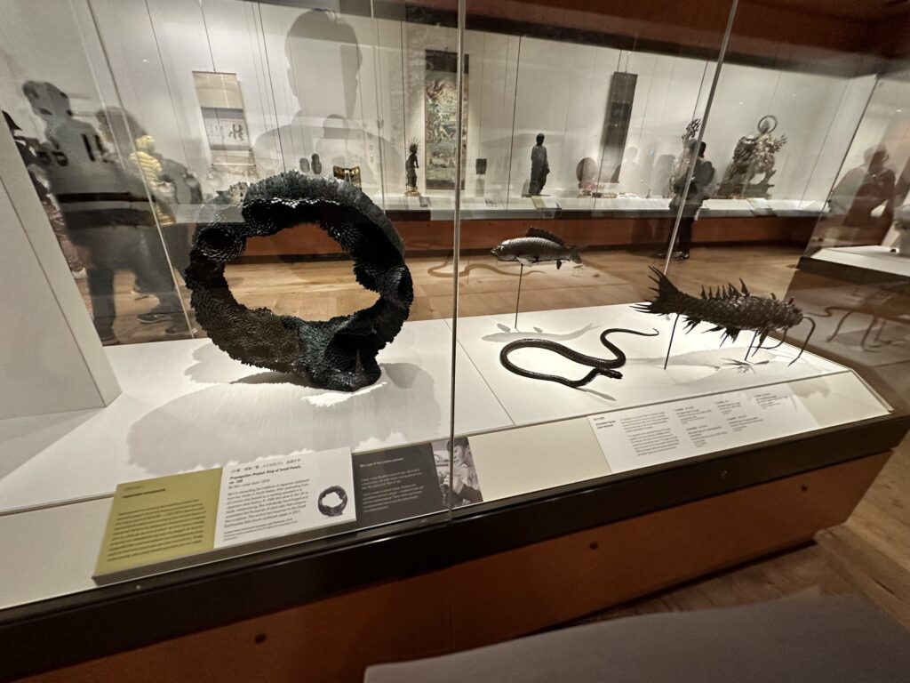 博物館の展示ケースに飾られた日本の美術品。手前には武士の鎧、奥には縄文土器、左には浮世絵が展示されている。