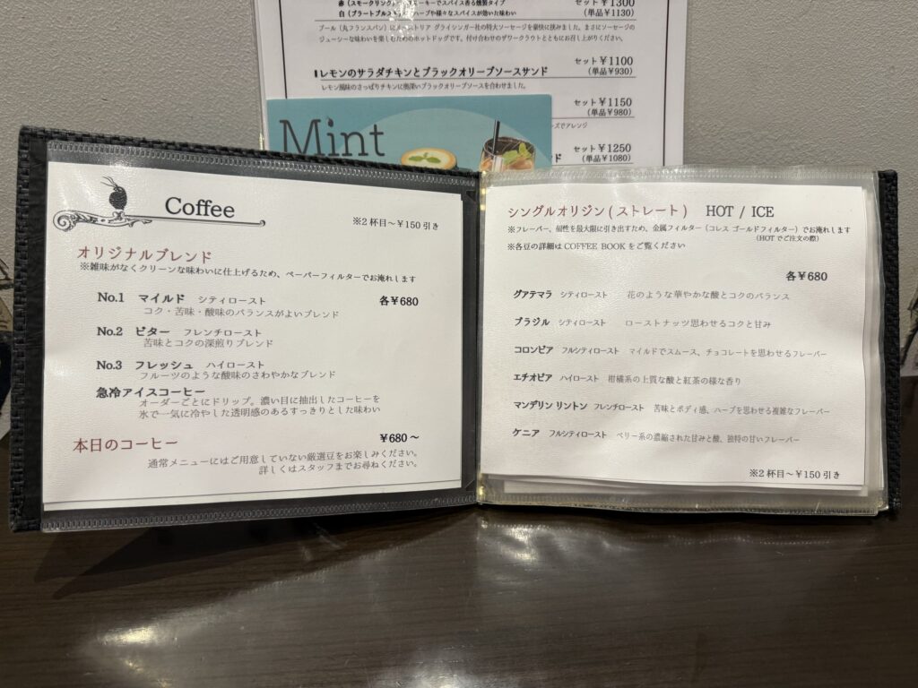 コーヒーメニューが書かれたボードのクローズアップ。オリジナルブレンドと6種類のシングルオリジンコーヒーが記載されている。