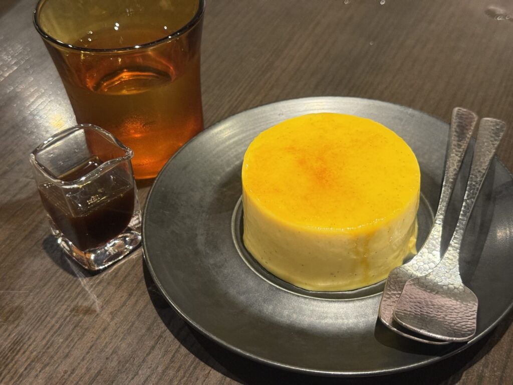 スプーンでカラメルを割った、濃厚そうなクリームブリュレのクローズアップ。滑らかなカスタードが見えている。
