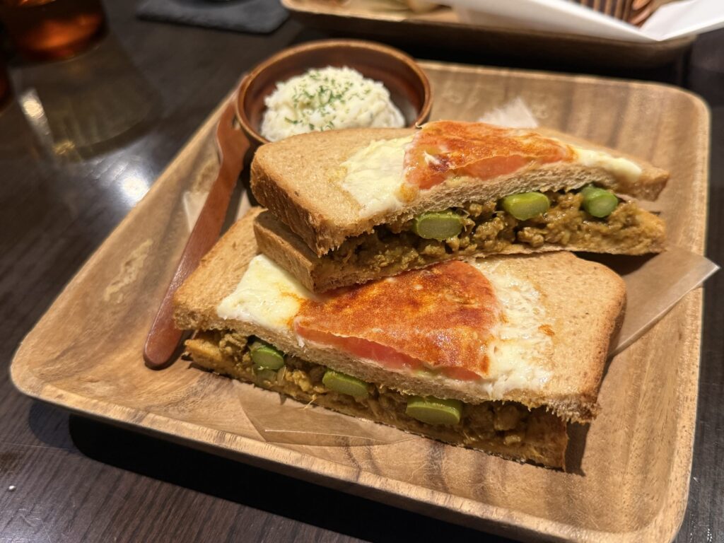 白い皿に乗った、半分にカットされたキーマカレーサンドイッチのクローズアップ。