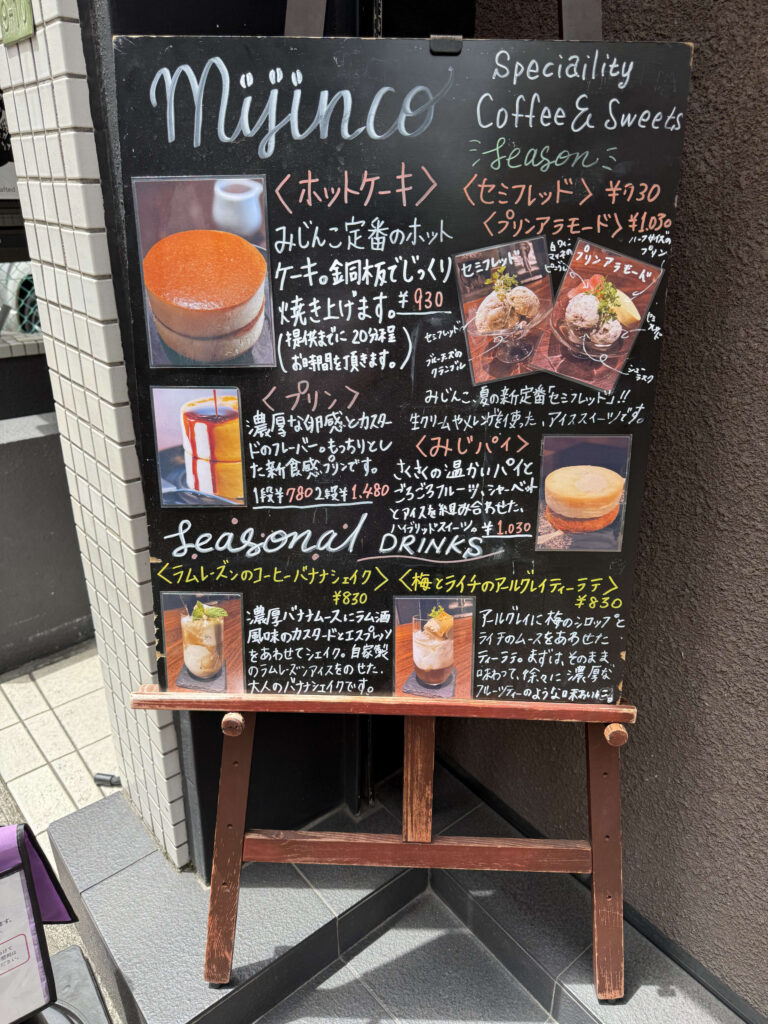 自家焙煎珈琲みじんこの手書きデザートメニューボード。ホットケーキ、プリン、チーズケーキなどのイラストが描かれている。