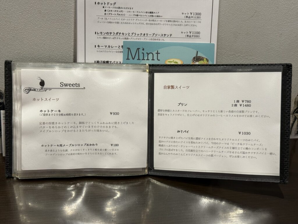 白い皿に乗った、カラメルソースとホイップクリームが添えられた固めタイプのカスタードプリン。