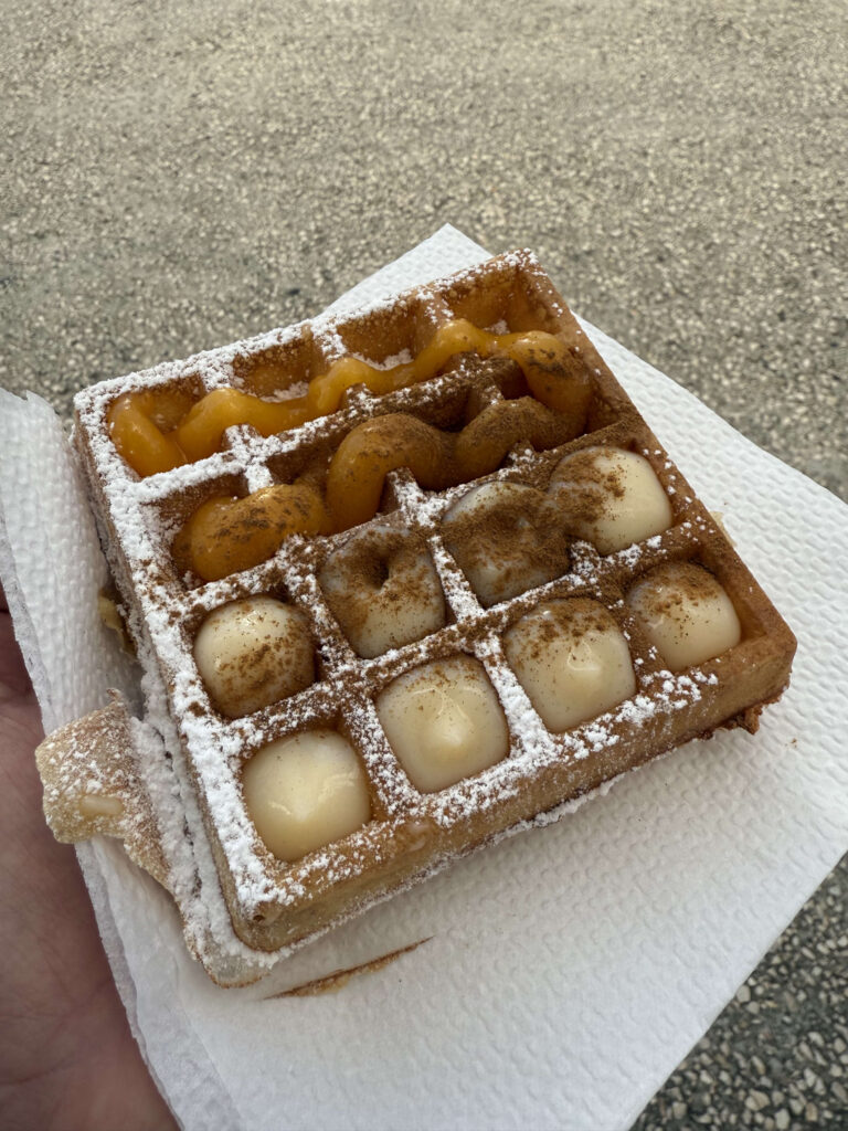 A waffle with powdered sugar in a paper container at the Web Summit venue.