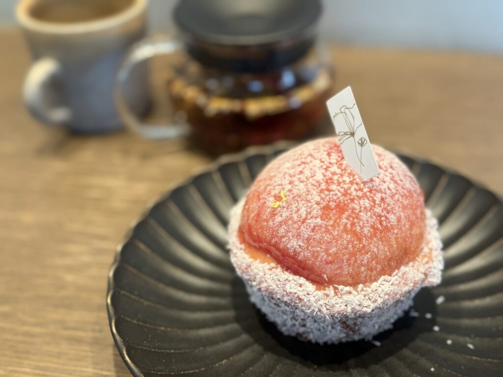 白いお皿の上に置かれた、スライスされた新鮮な桃がふんだんに乗った大きなホールタルト。