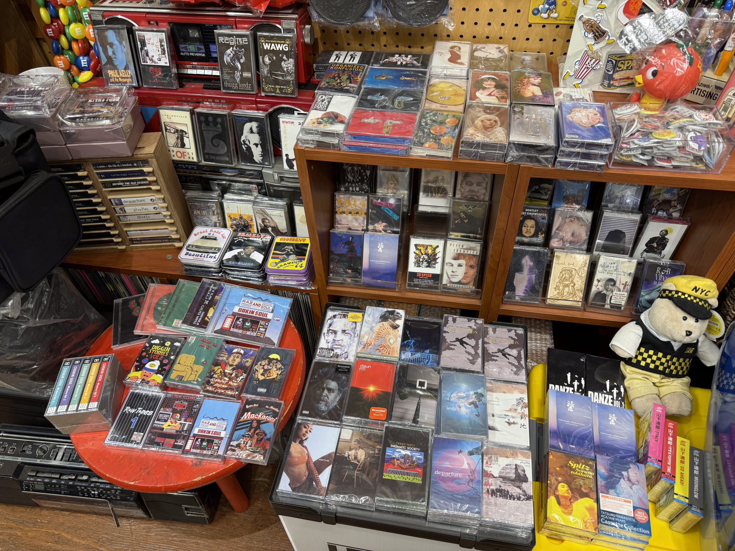 A wooden shelf lined with many cassette tapes, with a handwritten sign that says 'Hip-Hop, R&B, etc...'