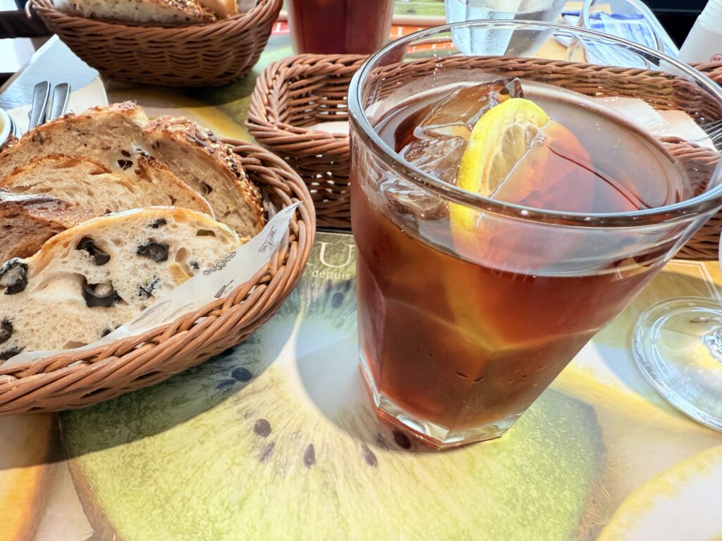 A glass of iced tea with a slice of lemon on the rim, placed on a wooden table.