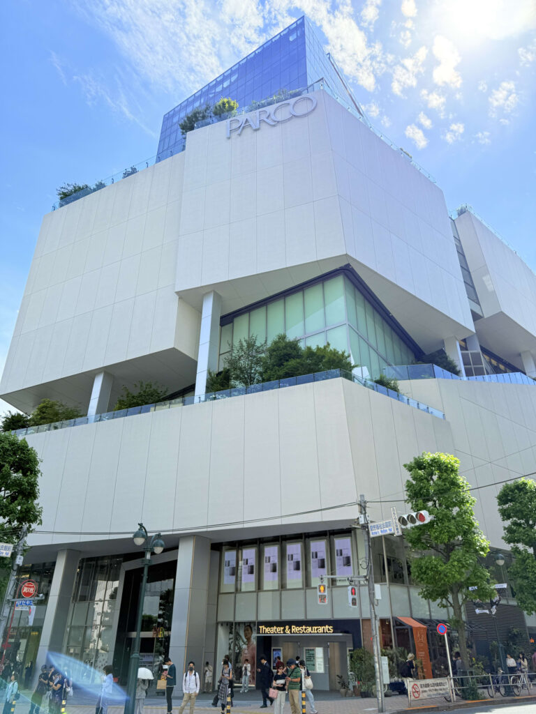 晴れた日の昼間、青空を背景にした渋谷PARCOの外観。幾何学的な建物に太陽の光が当たっている。