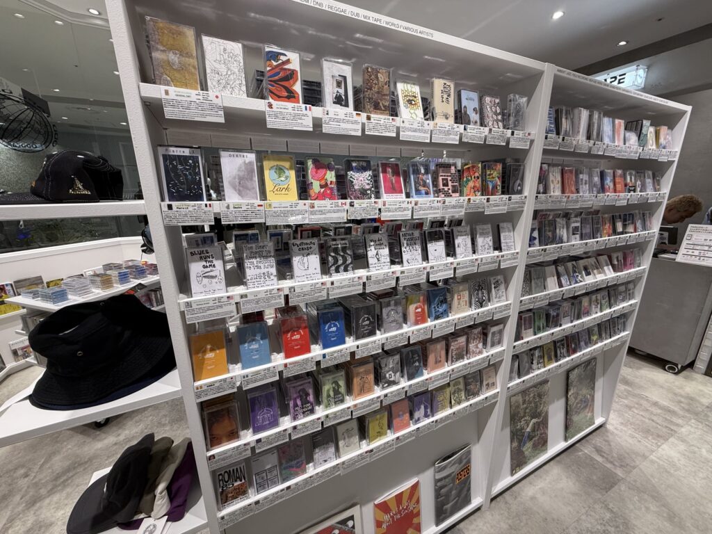 A wooden shelf packed tightly with cassette tapes of various genres, from indie to jazz.
