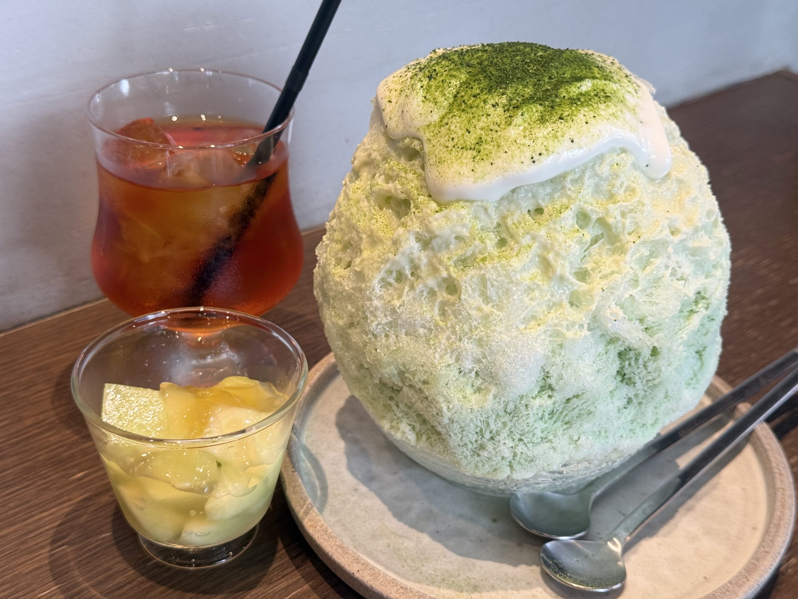 A large, heaping pile of shaved ice served in a hollowed-out melon bowl, with a cup of rooibos tea placed next to it.
