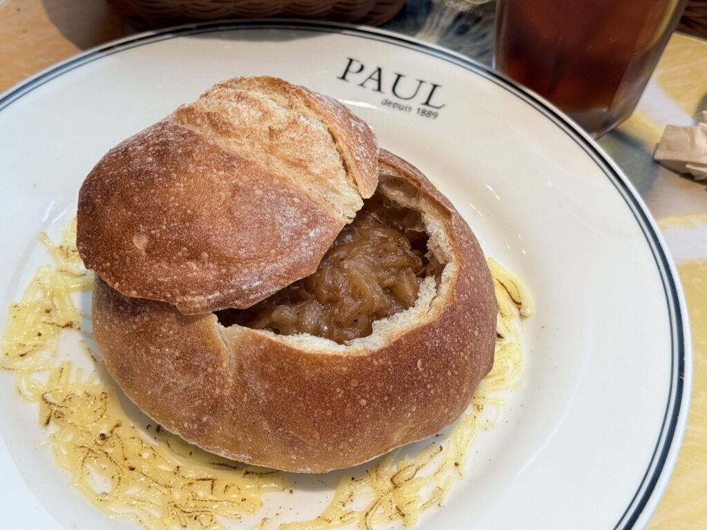 An onion soup bread, topped with melted cheese and onions and baked to a golden brown, sits on a white plate.