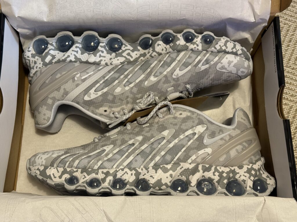 グレーと白のデジタルカモフラージュ柄のナイキ Air Max DN SPスニーカーが、靴箱の中に置かれている。特徴的なバブル状のエアユニットがソール部分に見える。