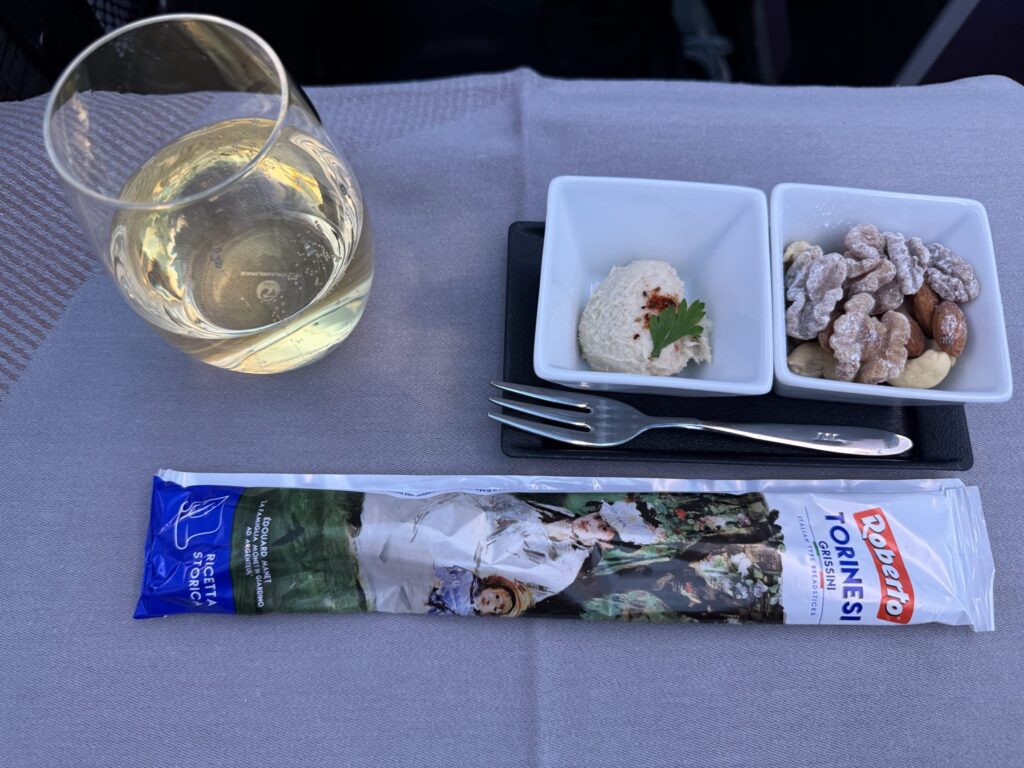 A glasse of champagne with a plate of appetizers blurred in the background.