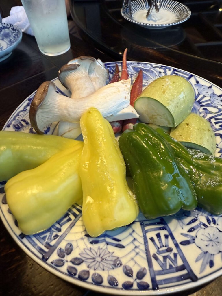 木製のトレイに盛られた、バナナピーマン、赤おくら、緑ピーマンなどの色鮮やかな夏野菜。