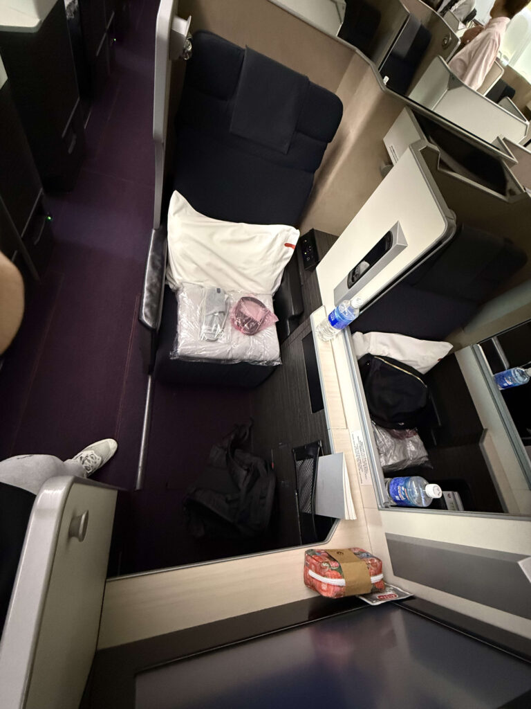 JALボーイング777のビジネスクラス「SKY SUITE」の窓側座席。大型モニターと木目調のテーブルが設置されている。