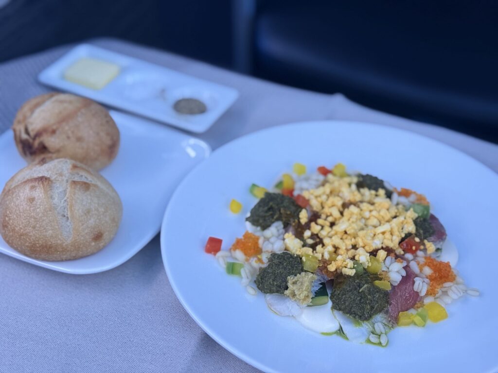 白い丸皿に盛り付けられたカンパチの刺身サラダ。新鮮なカンパチと緑の野菜が彩り豊かに見える。