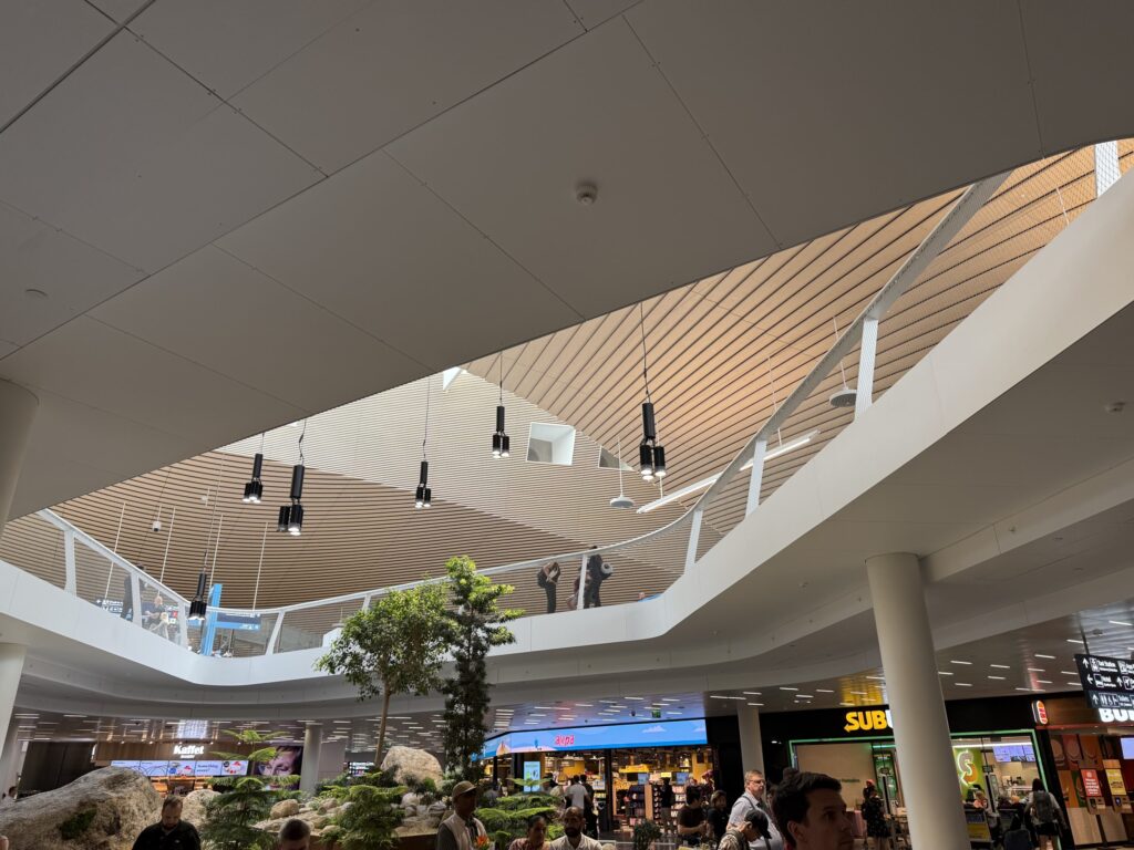 多くの旅行者が行き交う、広々として近代的なバンター国際空港の到着ロビー。天井が高く、床は光を反射して輝いている。