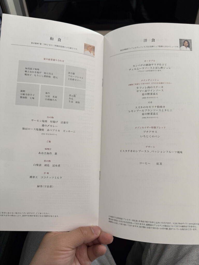 An open ANA Business Class in-flight meal menu resting on a tray table inside an airplane cabin.