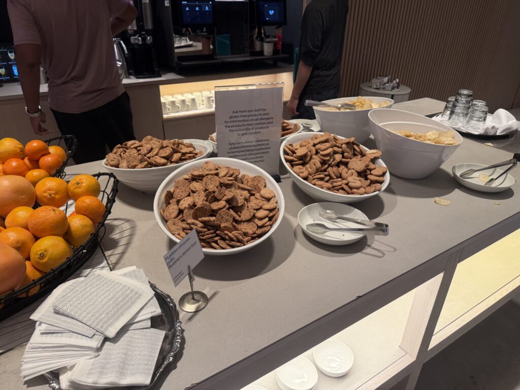 ビュッフェカウンターに並べられた、ジンジャークッキーやポテトチップスが入った白いボウルと、オレンジやグレープフルーツが盛られた黒いワイヤーバスケット。