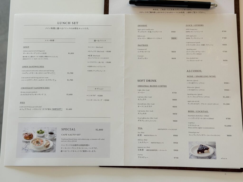 A two-page cafe menu in Japanese and English laid open on a light-colored table, showing various food and drink options.