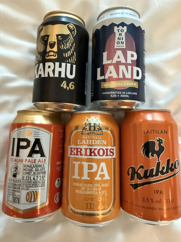 白い布の上に置かれた5種類のフィンランドのビール缶。カルフ、トルニオン・パニモ、オルヴィ、ラハデン・エリコイス、クッコのブランドが並んでいる。